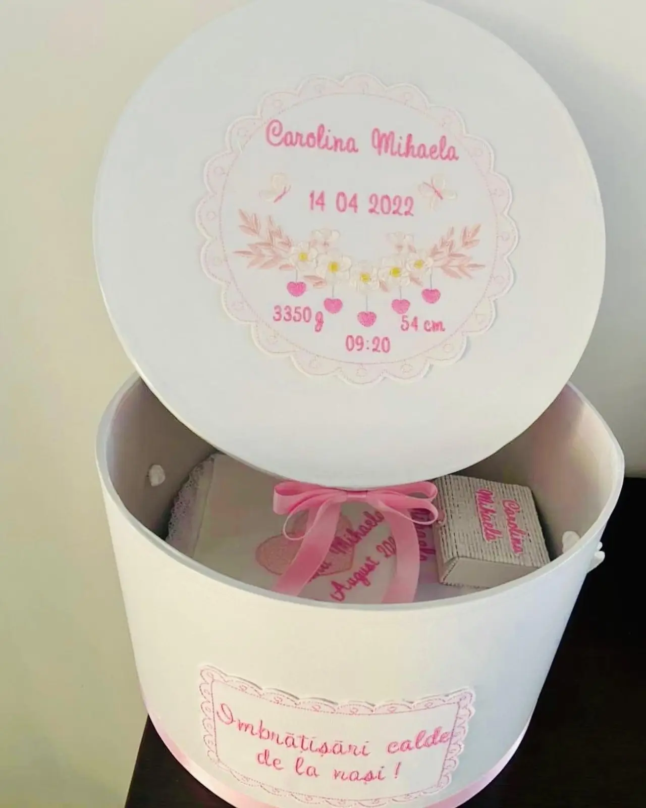 Cutie rotundă de trusou cu capac brodat cu flori, numele copilului, datele nașterii și un mesaj de la nași