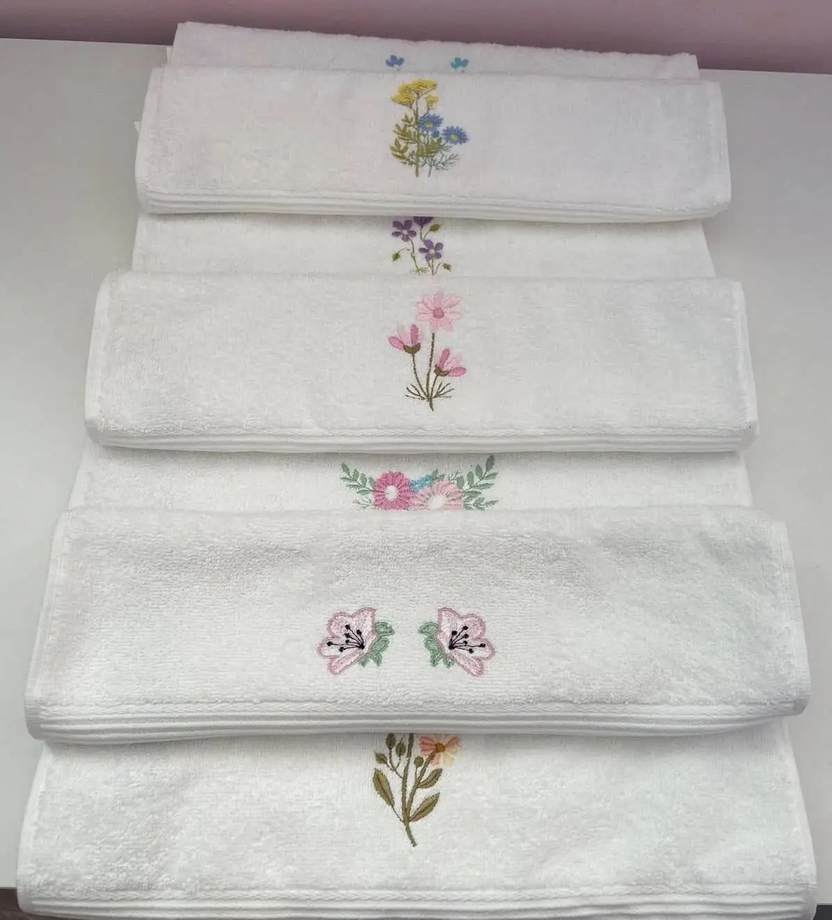Teanc de prosoape albe, fiecare brodat cu altă floare delicată