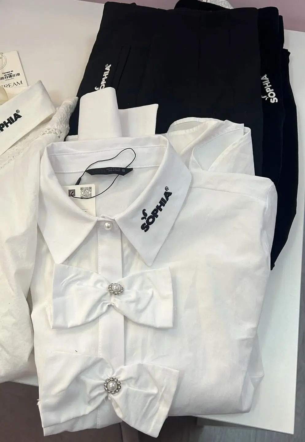 Cămăși albe și fuste negre de uniformă, brodate cu logo